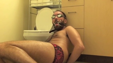 Estudioso latino de pecho peludo amarrado y amordazado con un Speedo ajustado.